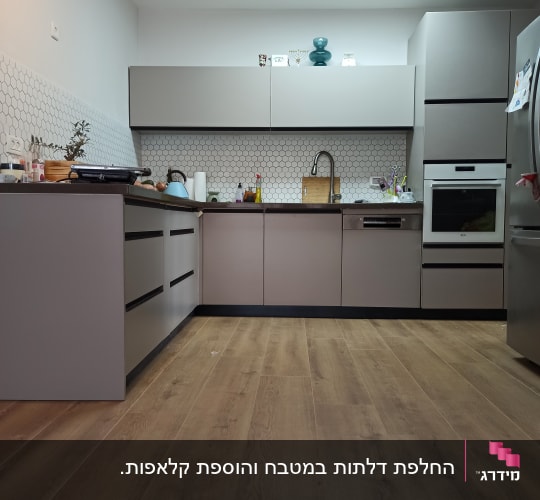 מטבח מודרני עם ארונות אפורים ורצפת עץ